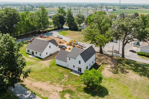 Aerial view of new farmhouse-style construction beside a barn-style building