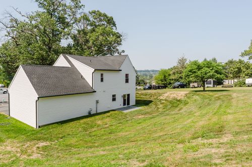 Aerial view of a gambrel-roof barn-style building near trees and a roadway