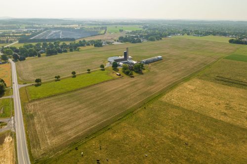 Aerial view of a farm property with a tall silo and cluster of barns amid green and gold fields