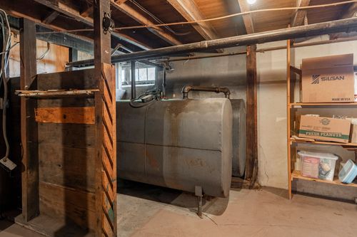 Basement storage area with an old oil tank and wood shelving stacked with boxes