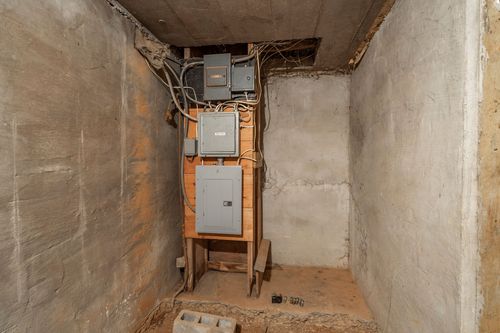 Basement utility closet housing an electrical panel and wiring on a wood frame