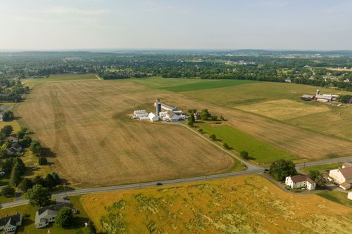 Aerial view of a farmstead with silo and barns surrounded by cropland near a small town