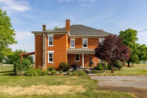 Close view of a brick farmhouse corner showing chimney and stone foundation
