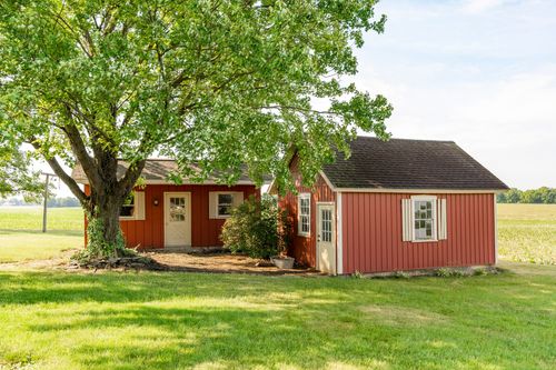 Red barn and matching storage building nestled beneath a large shade tree