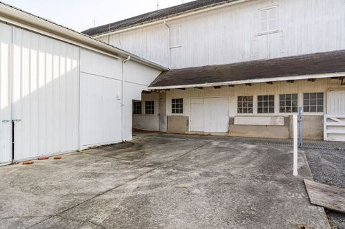 Close view of a white barn's covered breezeway with a stone foundation wall