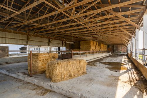 Interior of a hay barn with exposed wood trusses and stacked straw bales