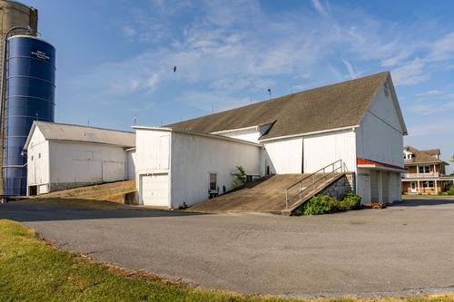 Barn complex with a grain silo, stone ramp and a house visible in the distance