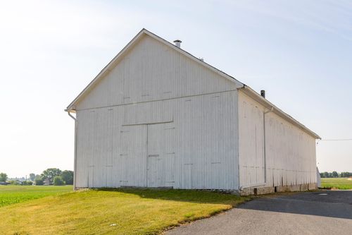 Close view of a white barn's gable end and board siding