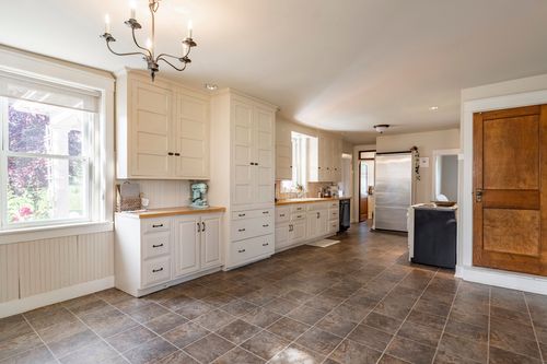 Kitchen with white cabinetry, wood countertops, a chandelier and a wood door