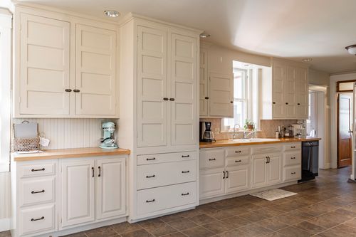 Kitchen with tall white pantry cabinetry, a coffee bar and built-in dishwasher