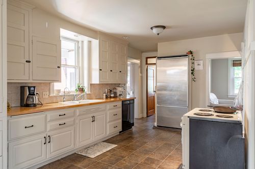 Kitchen with white cabinetry, wood countertops and a coffee station by the window