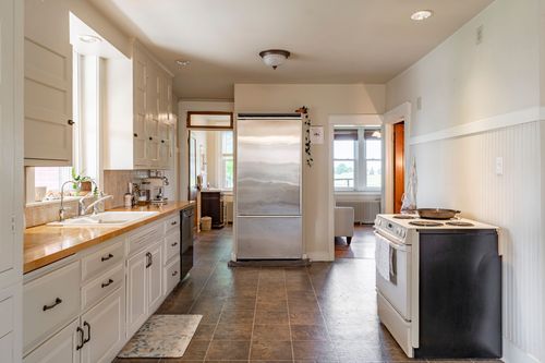 Kitchen with white cabinetry, stainless refrigerator and a black electric range