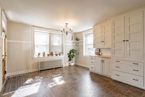 Sunlit room with a chandelier, potted plants on the windowsill and built-in white cabinetry