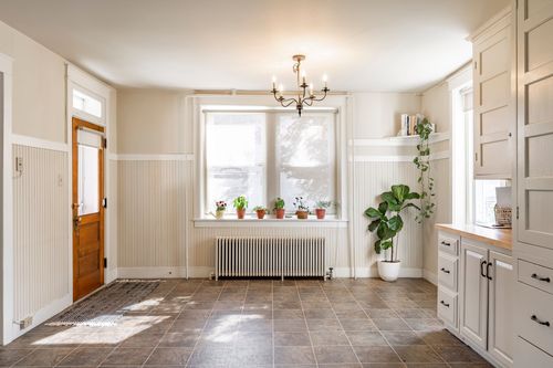Entry with a wood front door, chandelier, radiator and potted plants on the windowsill