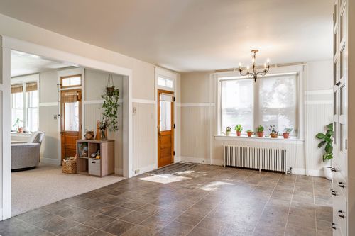 Foyer with a wood front door, chandelier and view into an adjoining sitting room