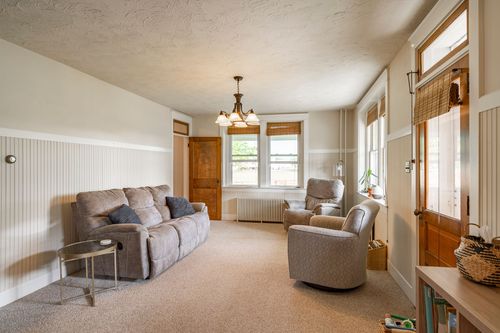 Living room with a tan reclining sofa, chandelier and an upholstered chair by the window
