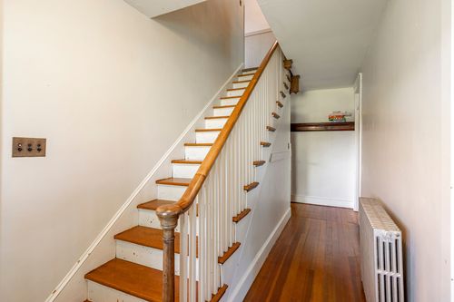 Hallway staircase with wood treads, white balusters and a radiator