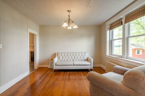 Home office with a wall-mounted TV, desk and view into an adjoining sitting room