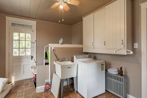 Laundry room with built-in cabinetry, a utility sink, top-load washer and radiator