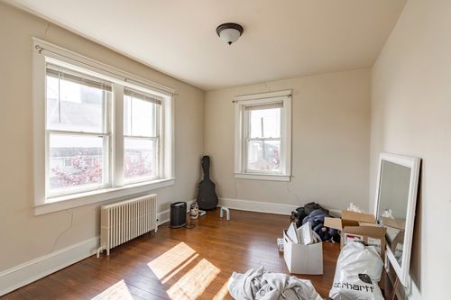 Bedroom with hardwood floors, tall double-hung windows and a radiator by the wall