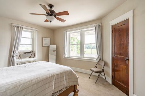 Bedroom with a wood bed, ceiling fan and two wood doors leading to a closet and hallway
