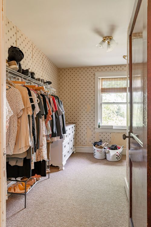 Walk-in closet with patterned wallpaper, wire shelving, clothes rack and a white dresser