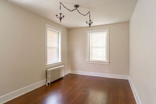 Empty carpeted room with a wrought iron double chandelier and two windows