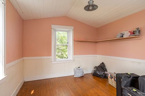 Attic bedroom with vaulted beadboard ceiling, pink walls, and a dormer window