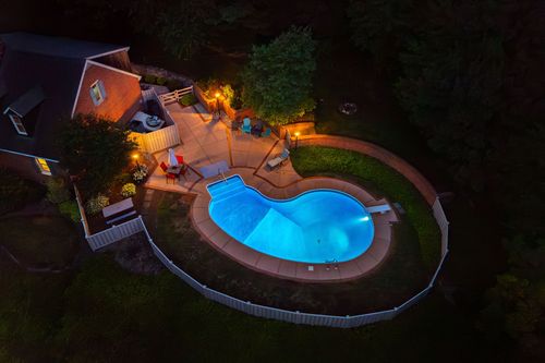 Aerial nighttime view of the pool and property lit up amid surrounding farmland