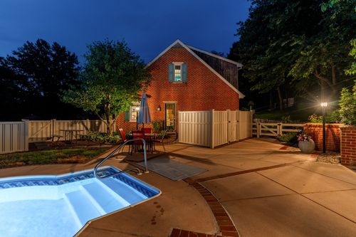 Twilight patio with dining table, umbrella, and a brick home behind a wood fence
