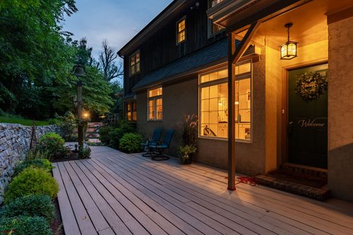 Twilight deck outside a lit home entrance with a welcome wreath on the door