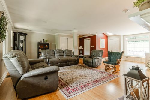 Open living room with leather recliners, patterned area rug, and hardwood floors