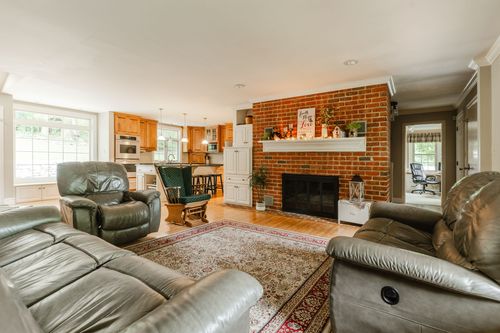 Living room with brick fireplace, leather sofas, and a view into the kitchen