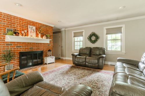 Living room with exposed brick fireplace, leather loveseat, and patterned rug