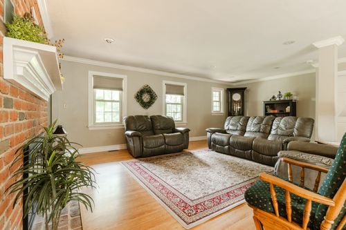 Living room with brick fireplace, leather seating, and a decorative wreath