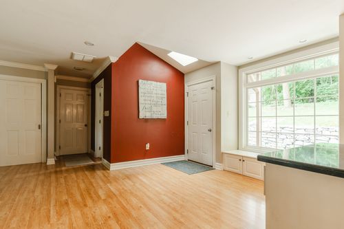 Entryway with a vaulted ceiling, terracotta accent wall, and hardwood floors