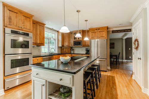 Kitchen with double wall ovens, stainless fridge, and a black granite island