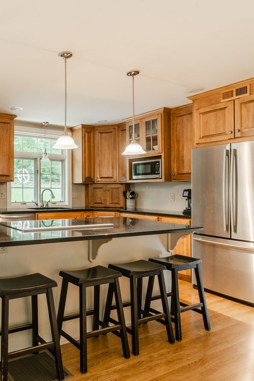 Kitchen with wood cabinets, black granite counters, and a stainless refrigerator