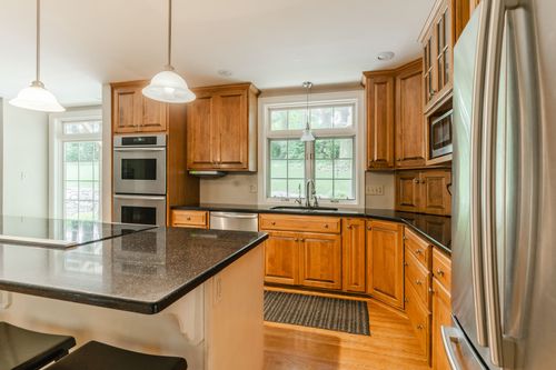 Kitchen corner with double wall ovens, wood cabinetry, and a garden window