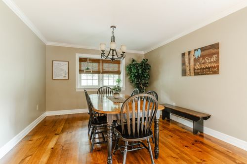 Dining room with oval wood table, ladderback chairs, and a wood bench