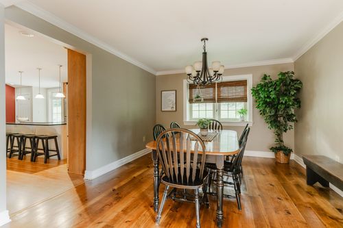 Dining room with round table, black chairs, and a view into the kitchen