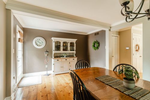 Dining room with wood table, white hutch, and a round wall clock
