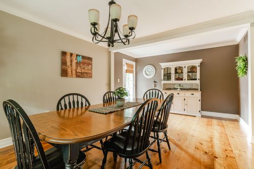 Dining room with long oak table, black chairs, and a white china hutch