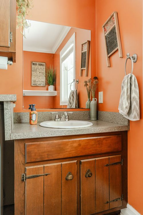 Bathroom vanity with terracotta walls, granite counter, and a wood cabinet base
