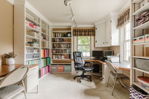 Home office with built-in bookshelves, a desk, and a window seating nook
