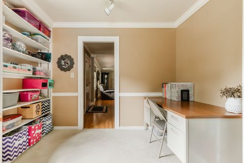 Home office with storage shelving, a wood desk, and a hallway view