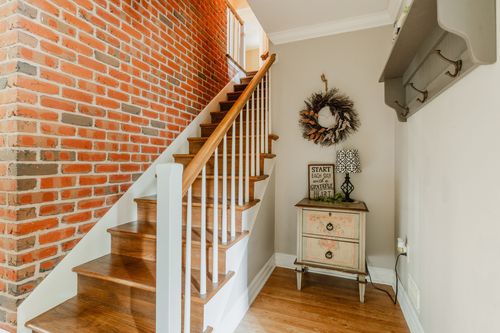 Foyer with a wood and brick staircase, a decorative wreath, and an accent table
