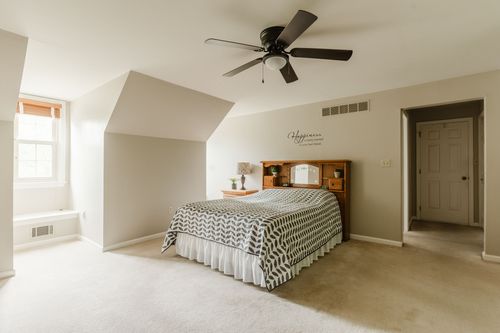 Bedroom with vaulted ceiling, ceiling fan, wood headboard, and a chevron comforter