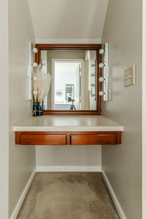 Built-in wood vanity nook with a large mirror and lighted sconces