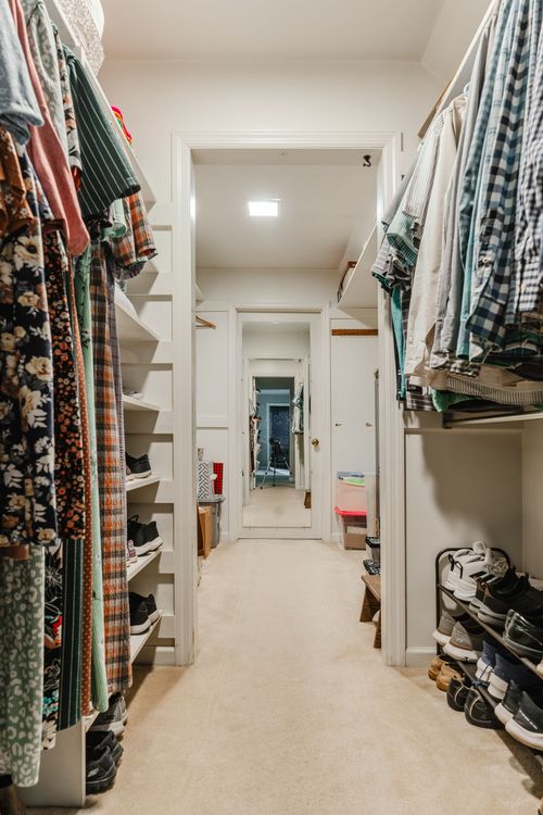 Walk-in closet with built-in shelving, hanging clothes, and a shoe rack
